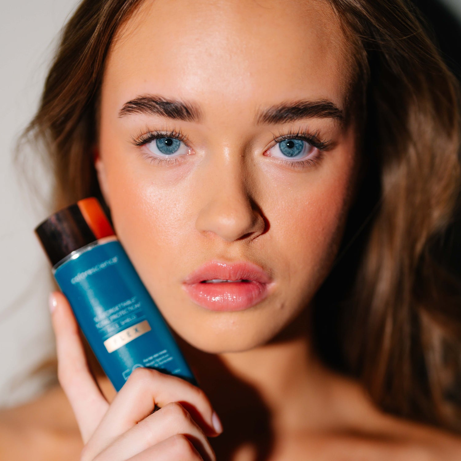 Kvinne holder solkrem med SPF 50 for å beskytte huden mot solens stråler