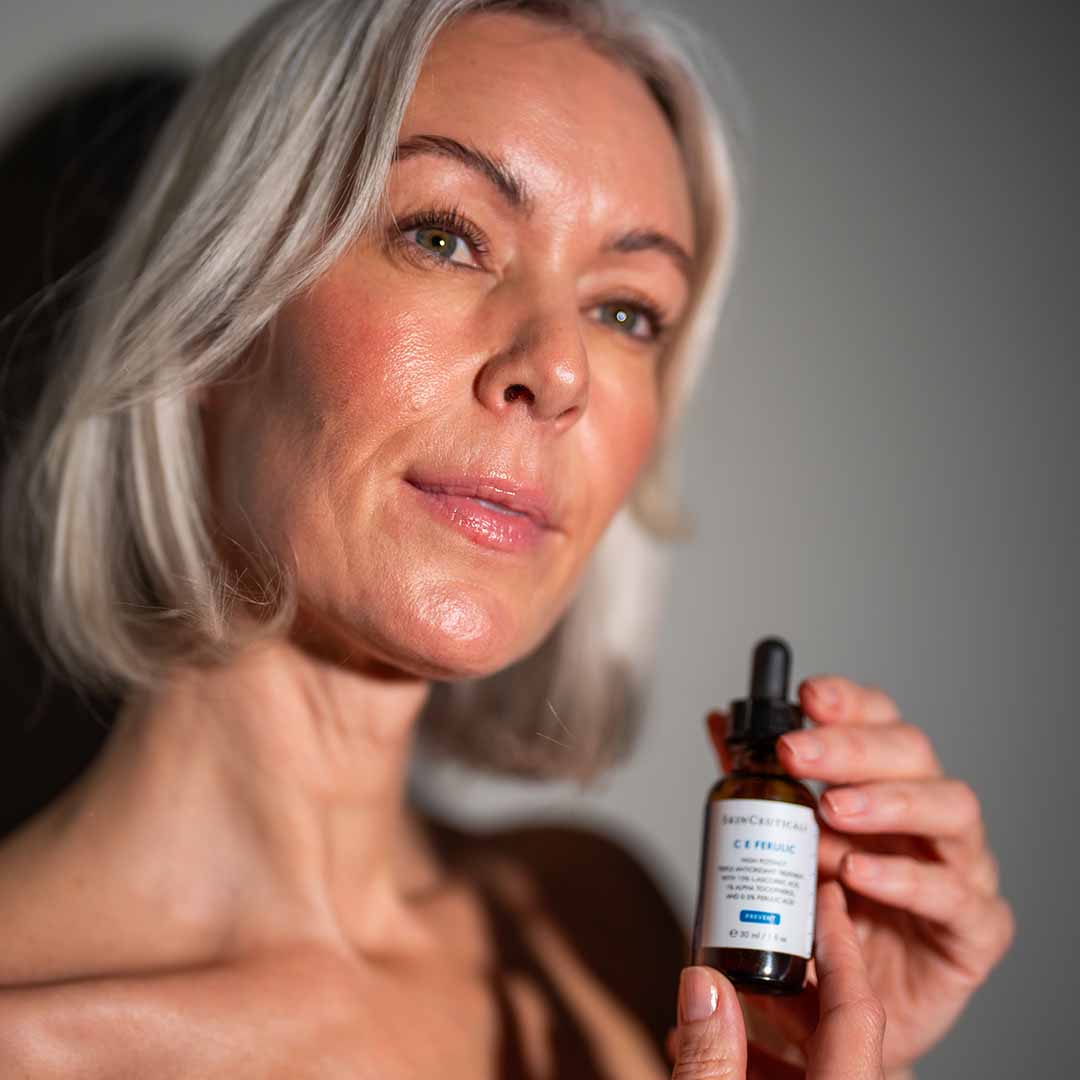 Voksen kvinne holder hudpleieserum fra SkinCeuticals som heter C E Ferulic og styrker hudbarrieren